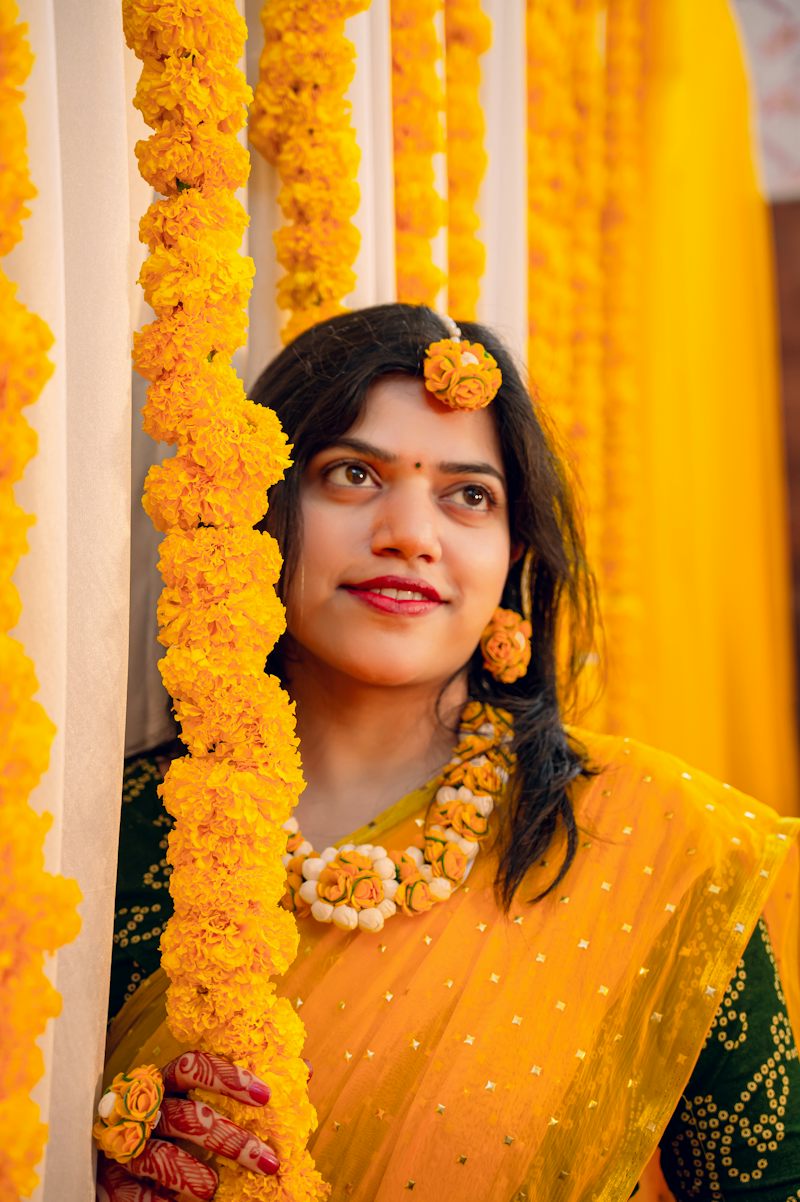 Bride smiling at her haldi among marigolds